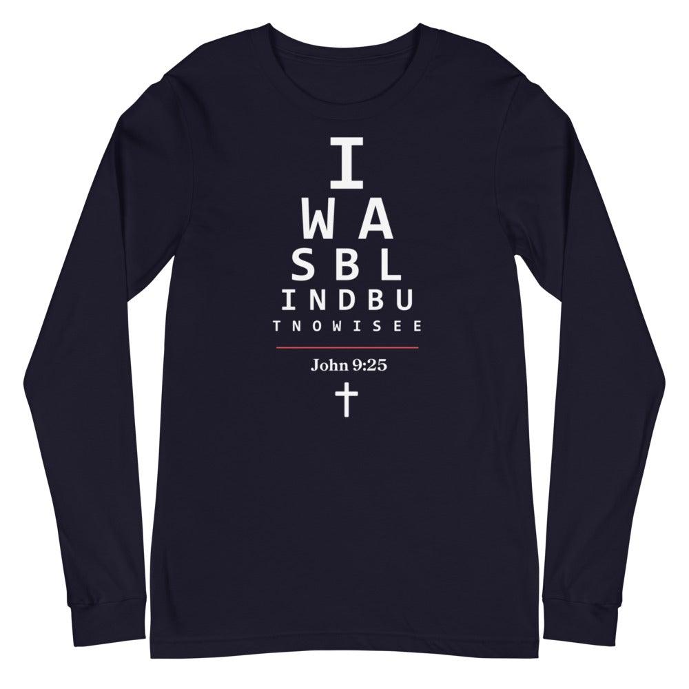 Flatlay of a long-sleeve navy Christian shirt.
The graphic is text as an eye chart, and it says "I WAS BLIND BUT NOW I SEE".
Below the text, there is a thin line, with text "John 9:25" and an icon of a cross below.