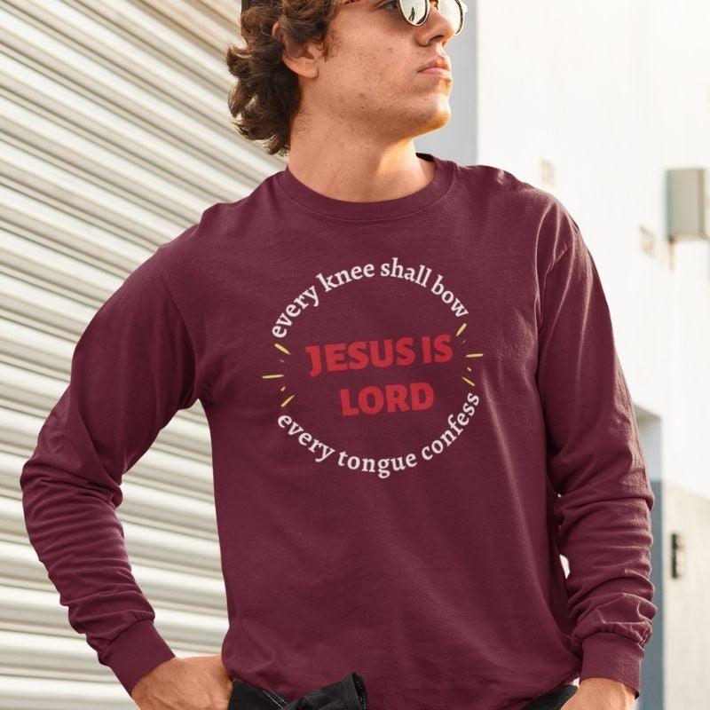 White man wearing maroon Christian unisex long sleeve shirt that says in a circle &quot;Every knee shall bow, every tongue confess&quot; with &quot;Jesus is Lord&quot; in the middle